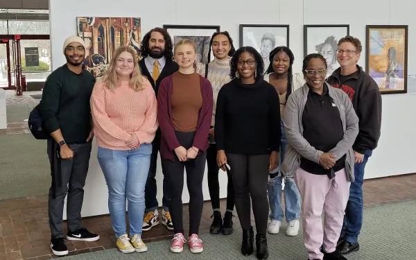 photo of team at afro American museum; 9 team member in front of hanging photos in museum gallery