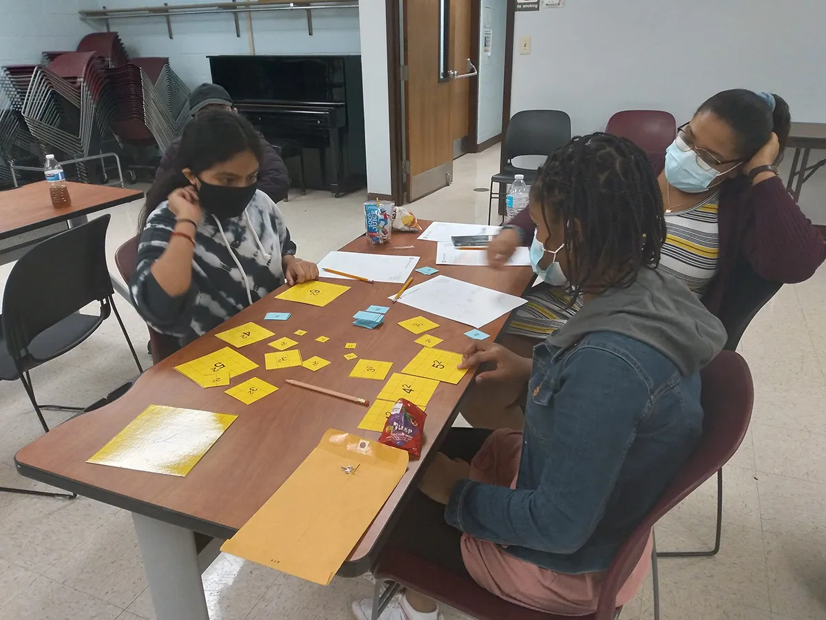 Two girls and a woman playing the sum of squares game.